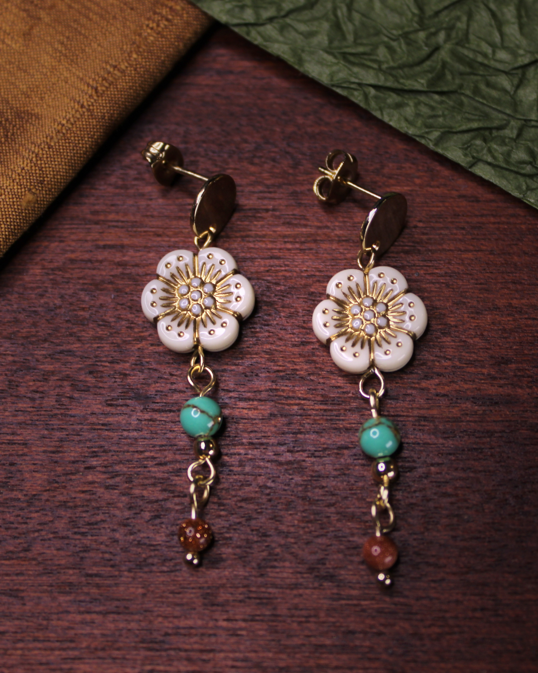 Gold colored circle earring stud with dangling bone white flower beads. 