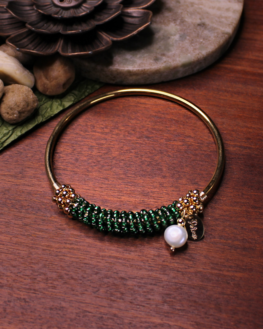 Gold colored bangle bracelet with wired gold and dark green crystal beads and freshwater pearl dangling bead.