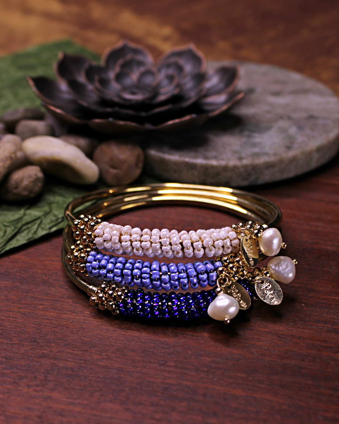 Gold colored bangle bracelet, set of three, with wired gold and bone white, cerulean blue, dark blue crystal beads and freshwater pearl dangling bead.