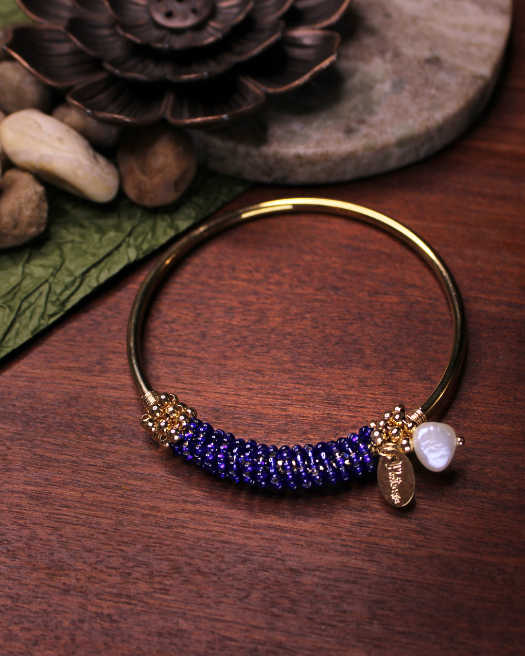 Gold colored bangle bracelet with wired gold and dark purple crystal beads and freshwater pearl dangling bead.