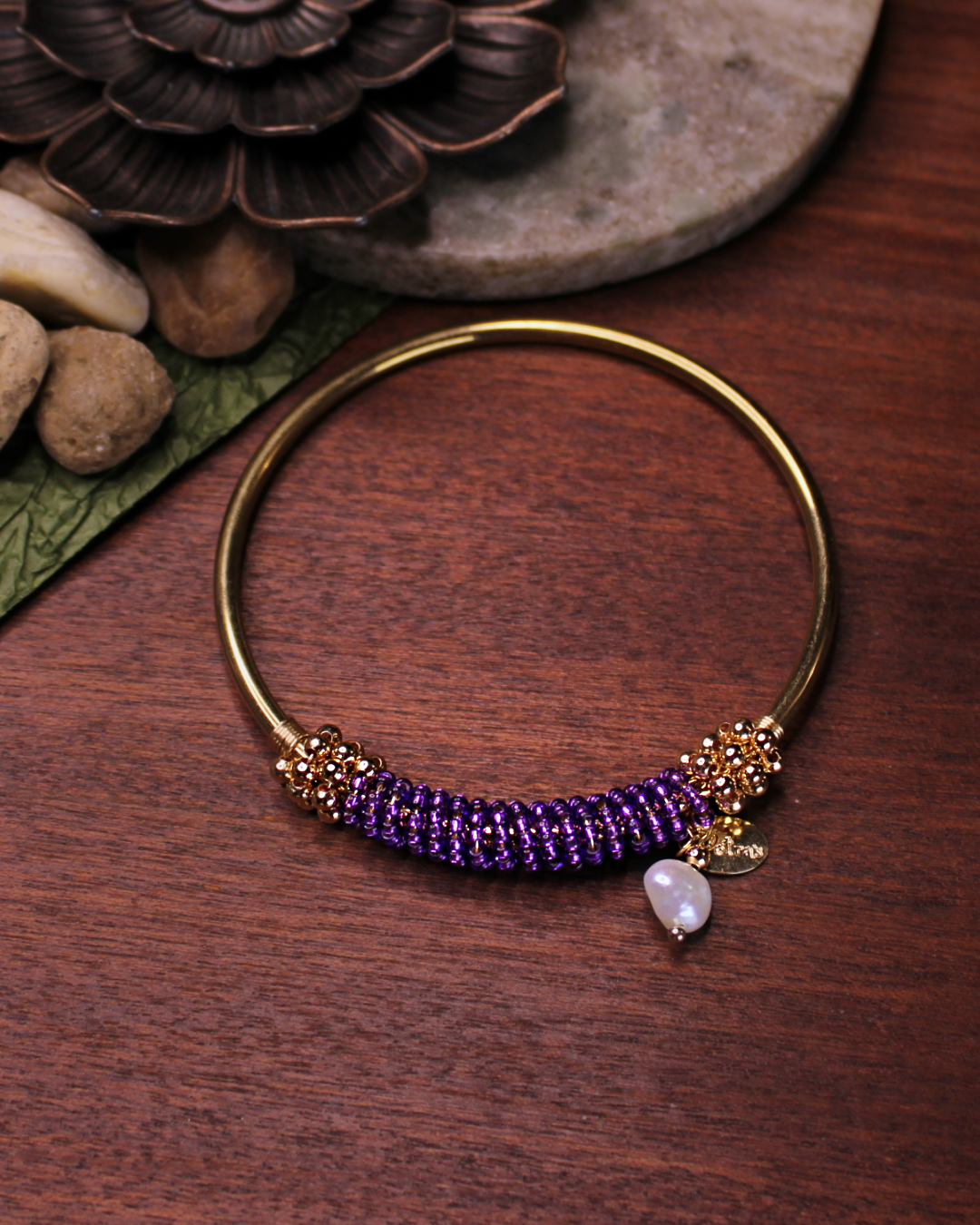 Gold colored bangle bracelet with wired gold and dark purple crystal beads and freshwater pearl dangling bead.