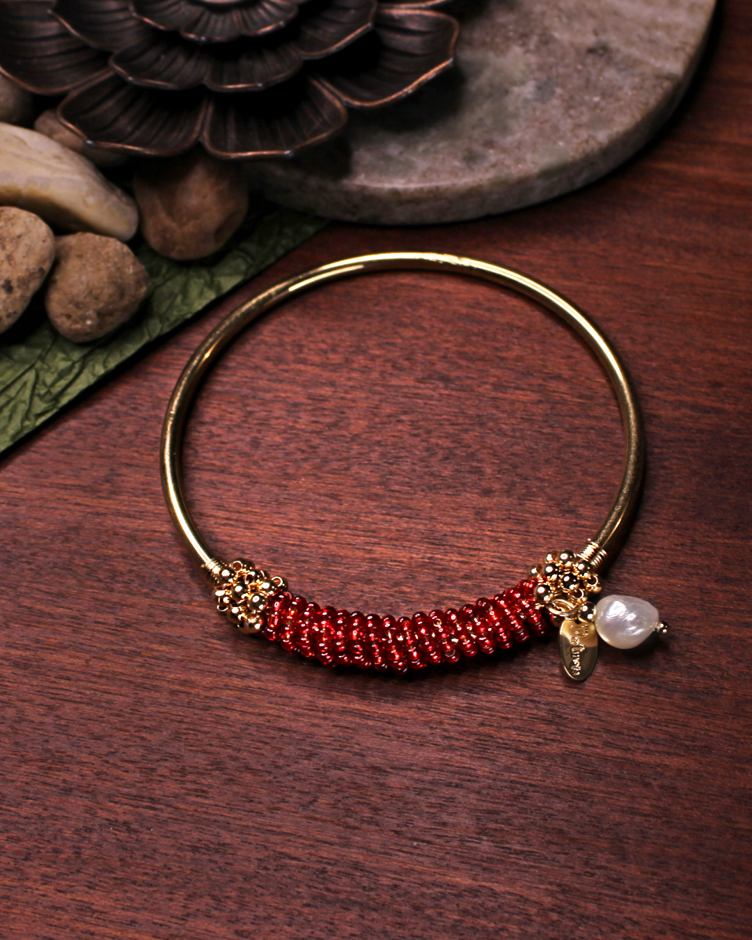 Gold colored bangle bracelet with wired gold and transparent red crystal beads and freshwater pearl dangling bead.