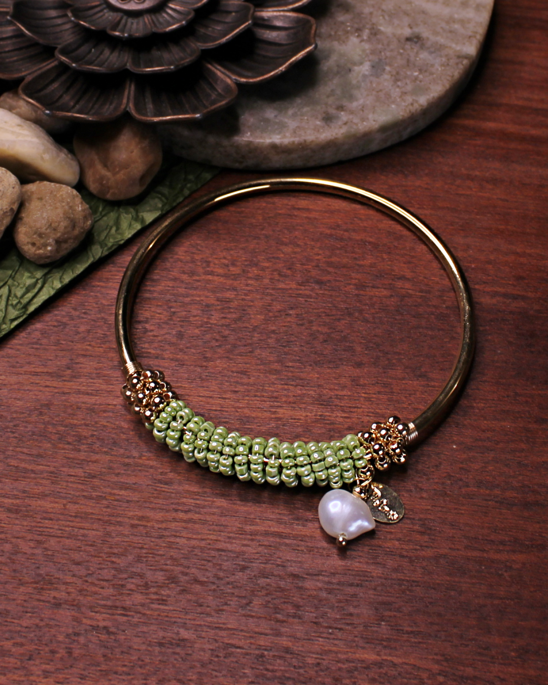 Gold colored bangle bracelet with wired gold and light green crystal beads and freshwater pearl dangling bead.