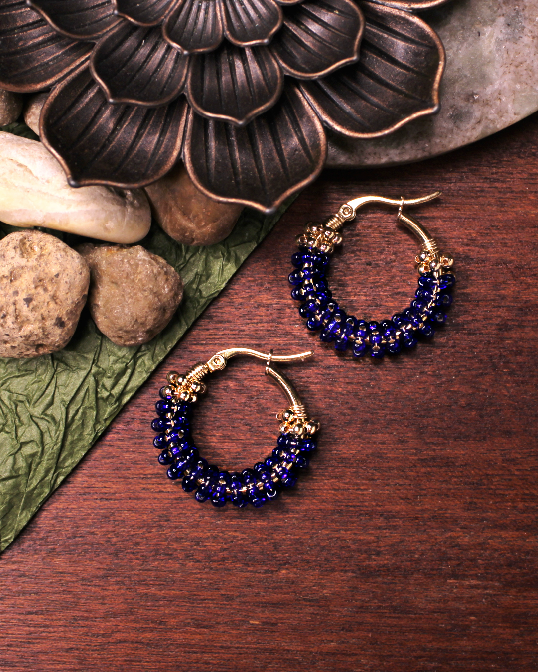 Small stainless steel gold colored hoop earrings with dark blue crystal seed beads.