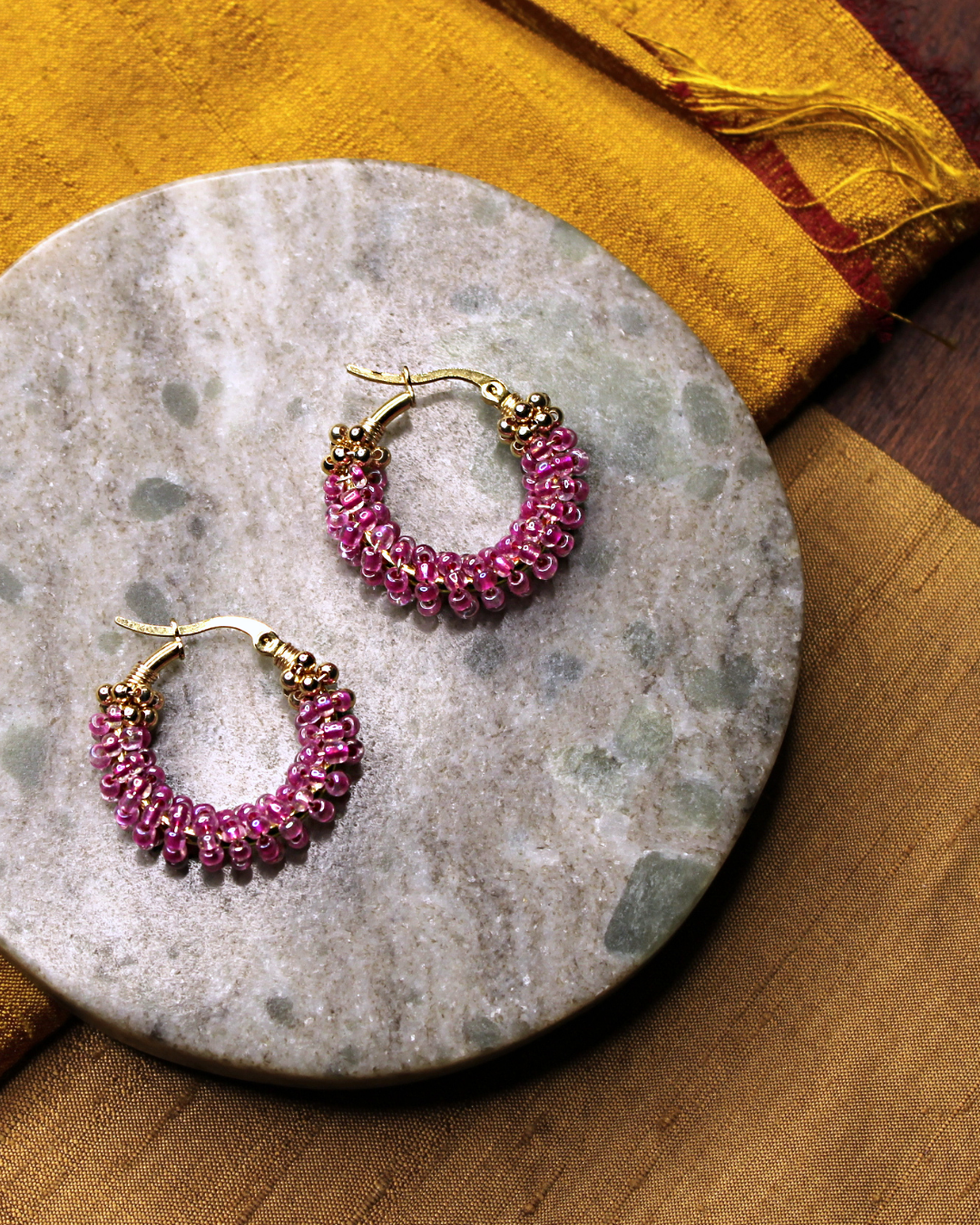 Small stainless steel gold colored hoop  earrings with transparent pink crystal seed beads.